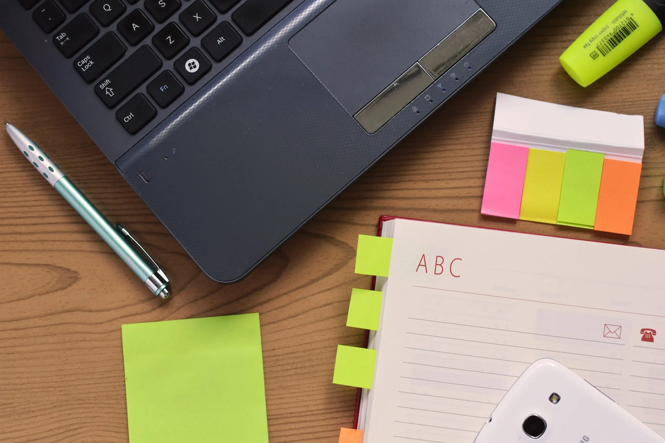 A laptop, notebook, and pen arranged on an office desk